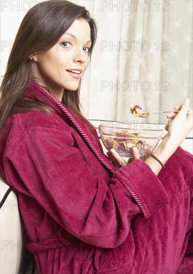 Mixed race woman eating cereal on sofa