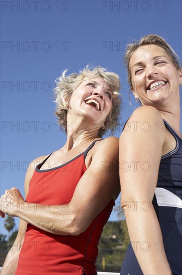 Women laughing back to back outdoors