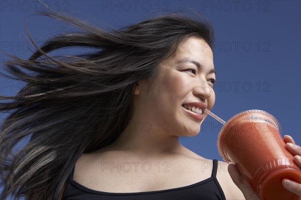 Chinese woman drinking smoothie outdoors