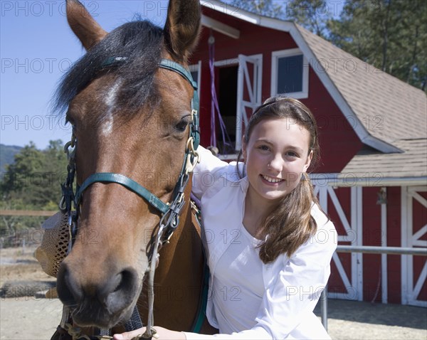 Mixed race girl smiling with horse on ranch