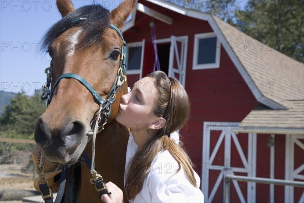 Mixed race girl kissing horse on ranch