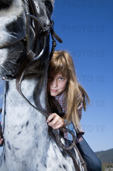 Mixed race girl riding horse on ranch