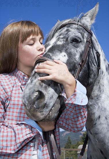 Mixed race girl kissing horse on ranch