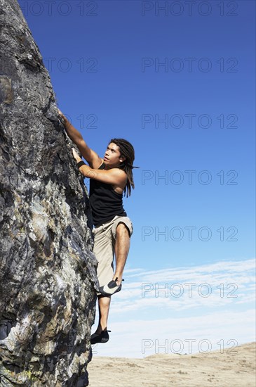 Hispanic climber scaling steep rock face