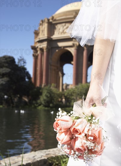 Chinese bride holding bouquet in urban park