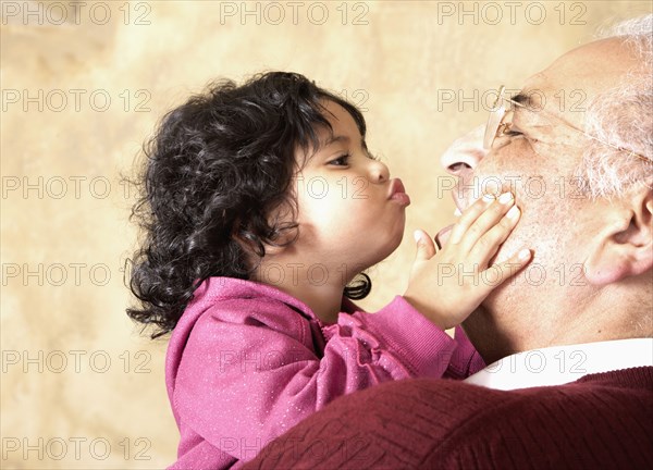 Hispanic girl kissing grandfather