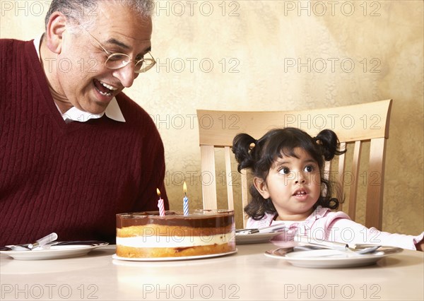 Senior Hispanic man and granddaughter celebrating birthday