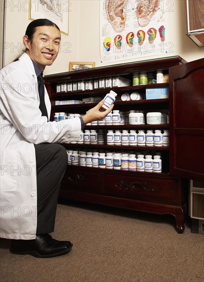 Chinese medicine practitioner selecting herbs from cabinet