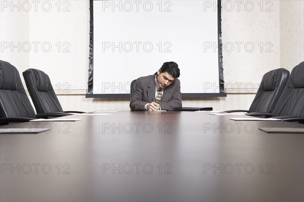 Mixed race businessman sitting at conference table