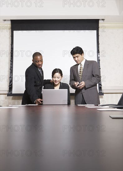 Business people using laptop at conference table