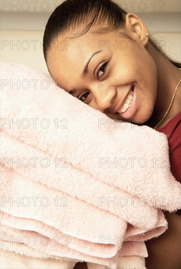 African American woman carrying stack of towels