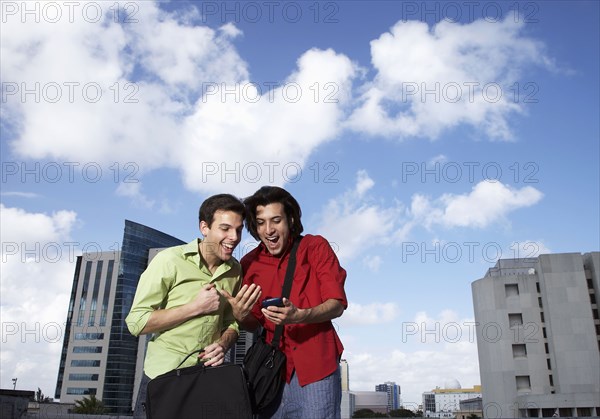 Hispanic men using cell phone on city street