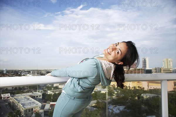 Hispanic woman on balcony overlooking urban cityscape