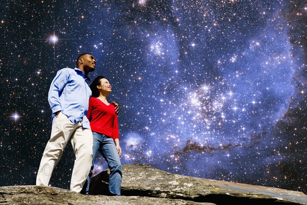 Couple admiring galaxy from rock formation