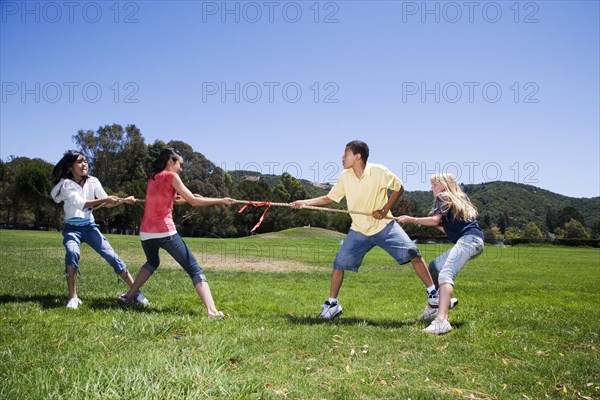 Children playing tug-of-war in field