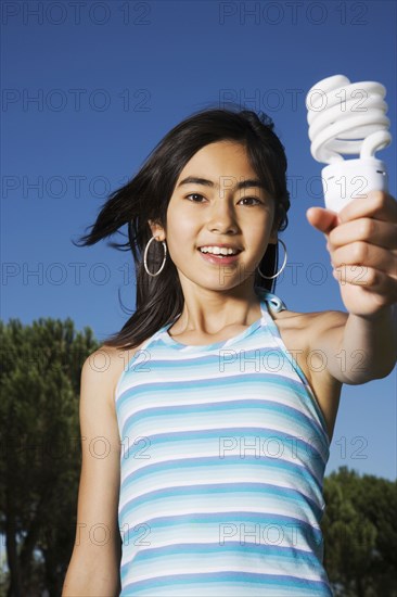 Chinese girl holding light bulb outdoors