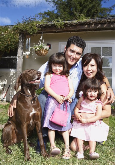 Family smiling together with dog in backyard