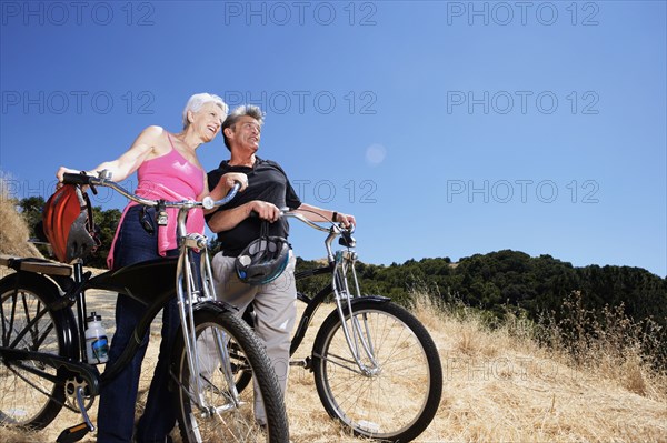 Senior Caucasian couple wheeling dirt bikes on hilltop