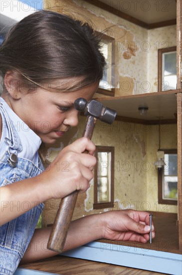 Mixed race girl fixing doll house