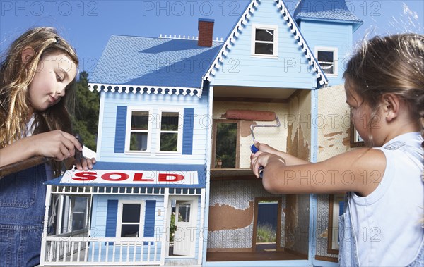 Mixed race girls fixing up doll house for sale