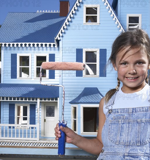 Mixed race girl painting doll house