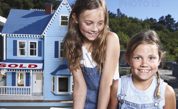 Mixed race girls smiling by doll house