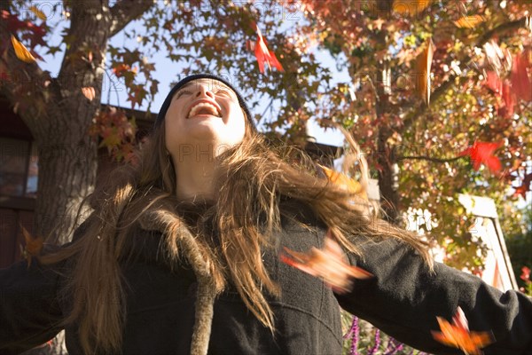 Caucasian woman playing in fall leaves