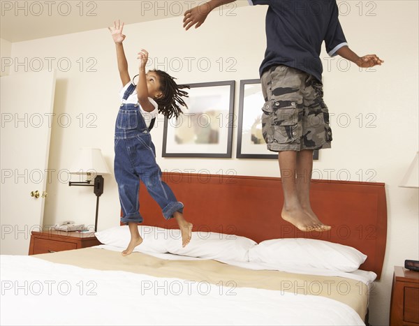 Black children jumping on bed