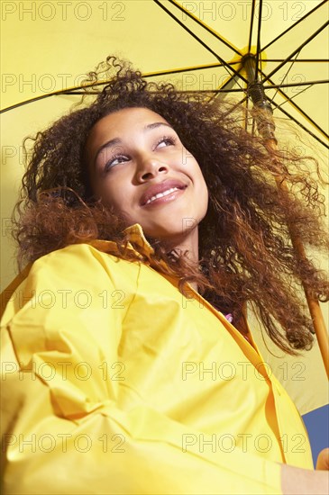 Mixed race woman standing under umbrella