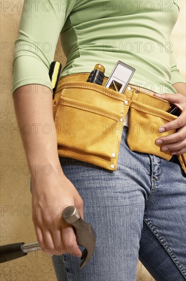 Mixed race woman wearing tool belt