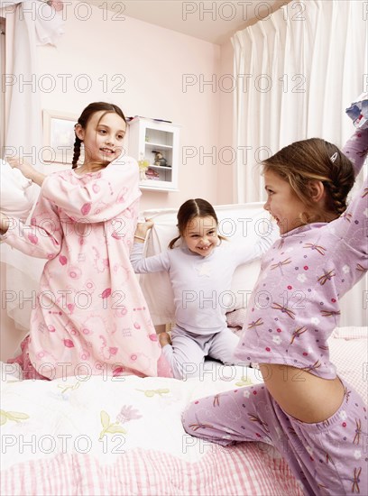 Mixed race girls having pillow fight on bed