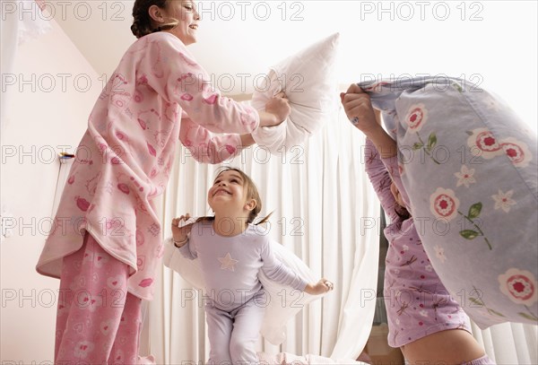 Mixed race girls having pillow fight on bed