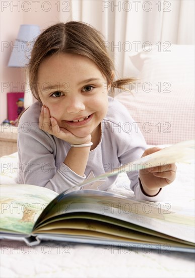 Mixed race girl reading on bed