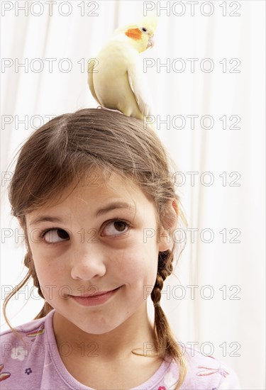 Mixed race girl holding bird on head