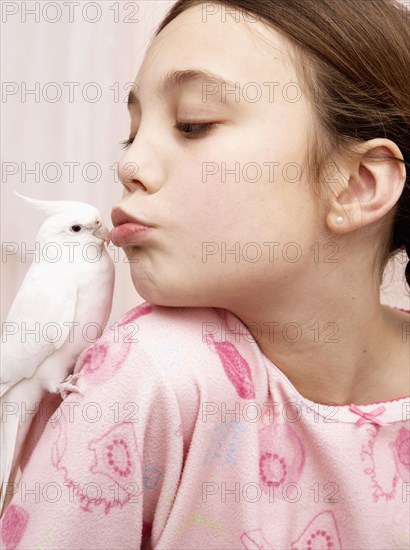 Mixed race girl kissing bird