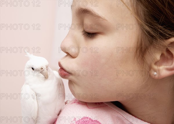 Mixed race girl kissing bird