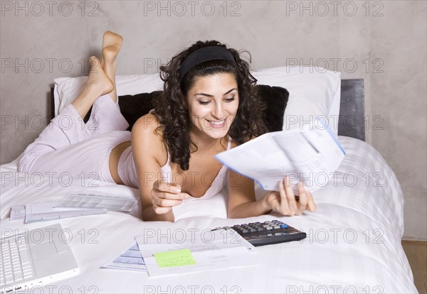 Persian woman paying bills on bed