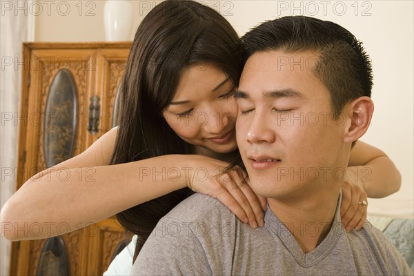 Chinese woman giving boyfriend shoulder massage