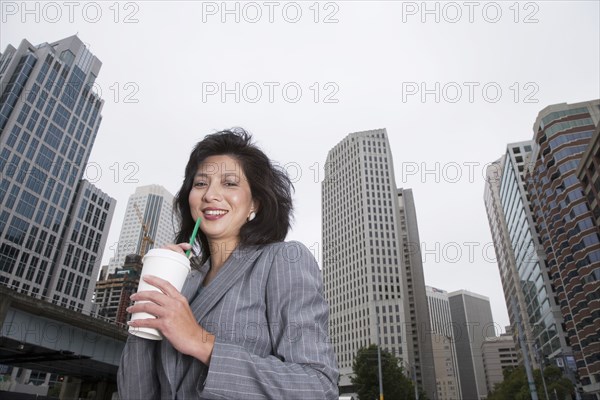 Chinese businesswoman drinking coffee on city street