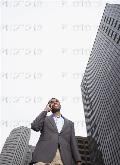 Mixed businessman talking on cell phone on city street