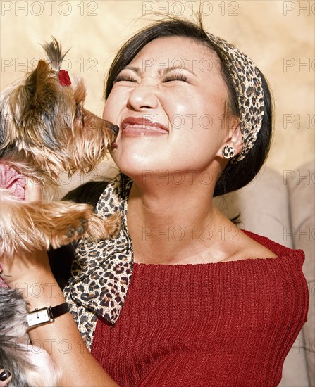 Asian woman holding dog on sofa