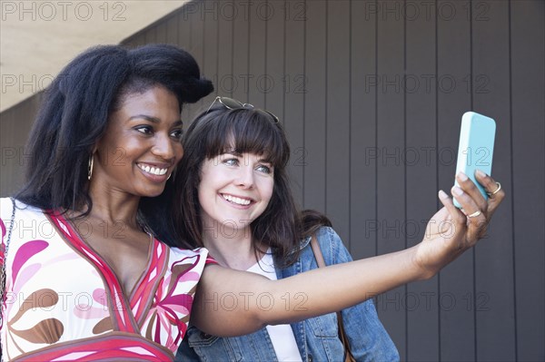 Women taking cell phone picture together outdoors