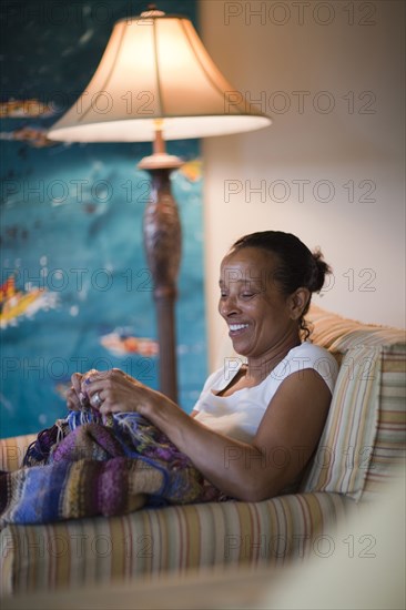 Mixed race woman knitting blanket