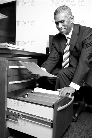 African American businessman putting paperwork in drawer