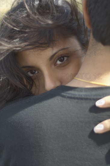 Middle Eastern woman looking over man's shoulder