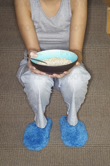 Asian woman eating cereal on stairs