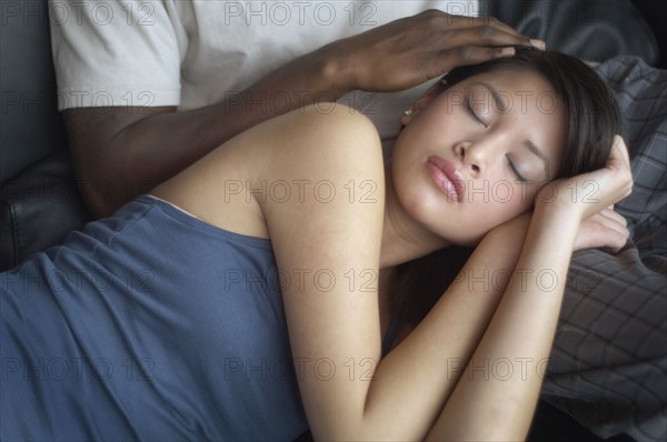 Multi-ethnic couple cuddling on sofa