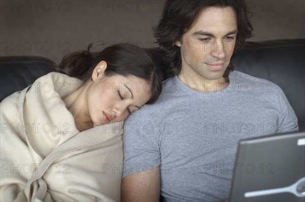 Multi-ethnic couple cuddling on sofa