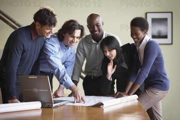 Multi-ethnic businesspeople looking at blueprints