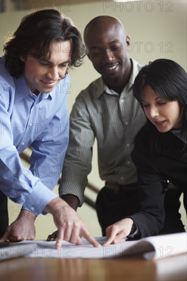 Multi-ethnic businesspeople looking at blueprints